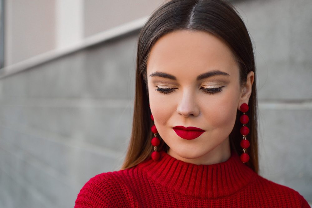 girl wearing red sweater with matching lipstick looking down