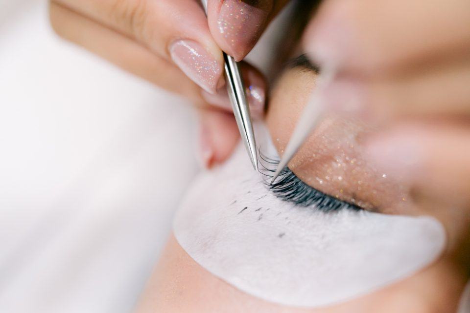 esthetician placing eyelash extensions on client (close up)