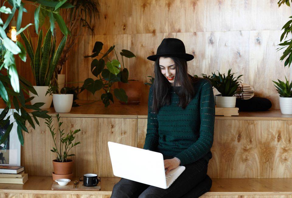 trendy girl working on her computer with plants all around her