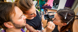 A man teaching a woman how to do makeup