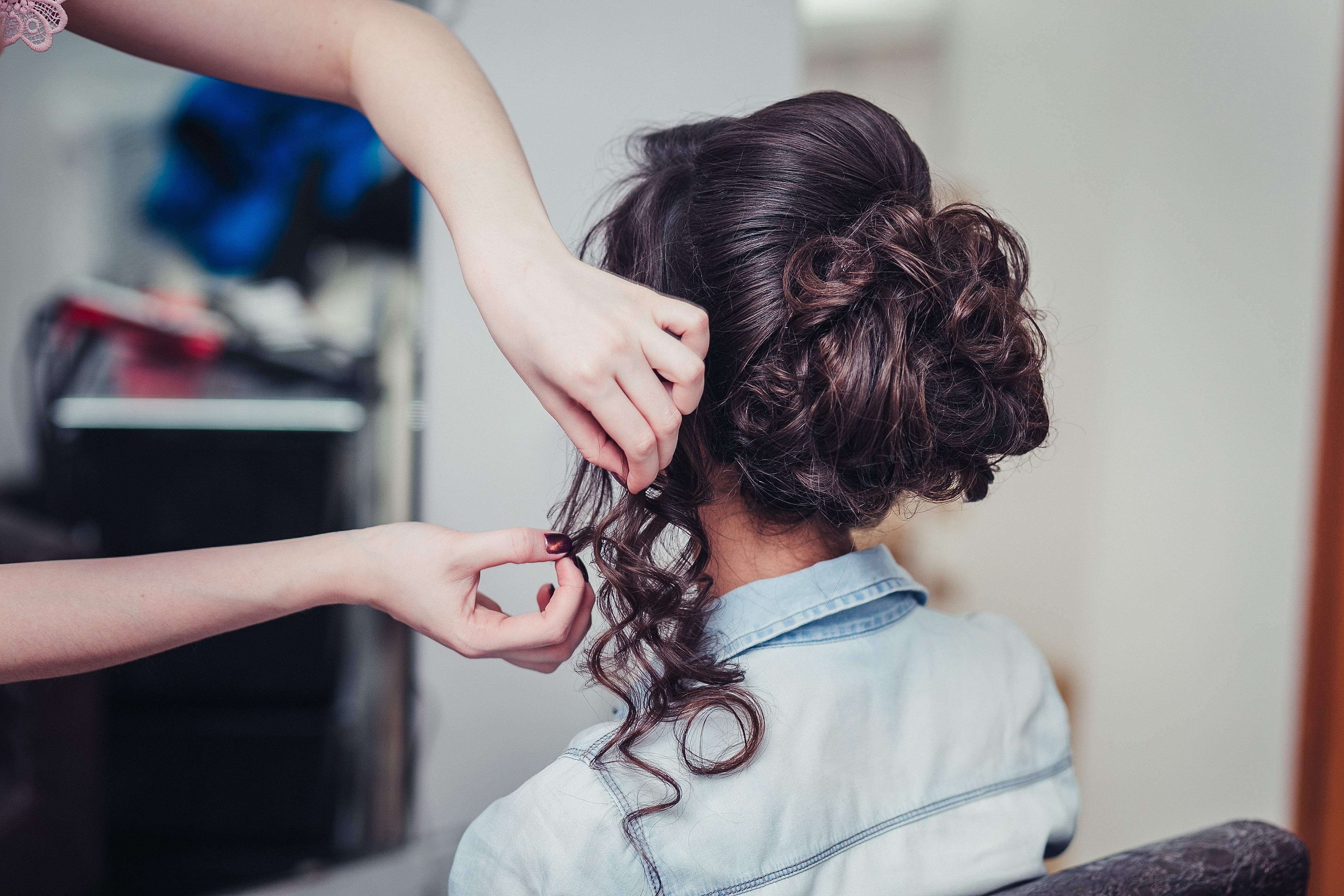 woman from the back having hair curled into fancy updo