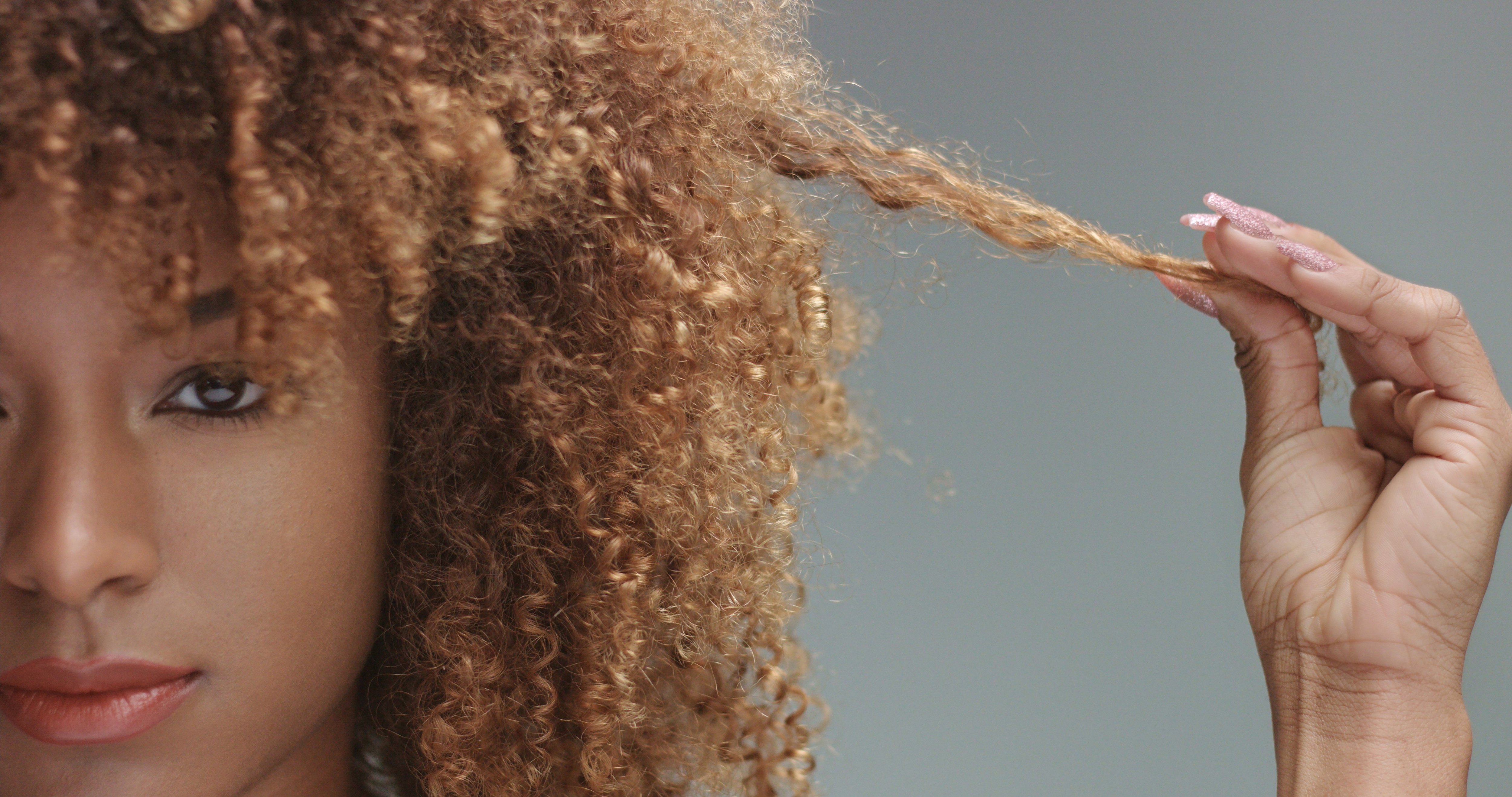 Curly haired woman pulling one curl straight out to the side