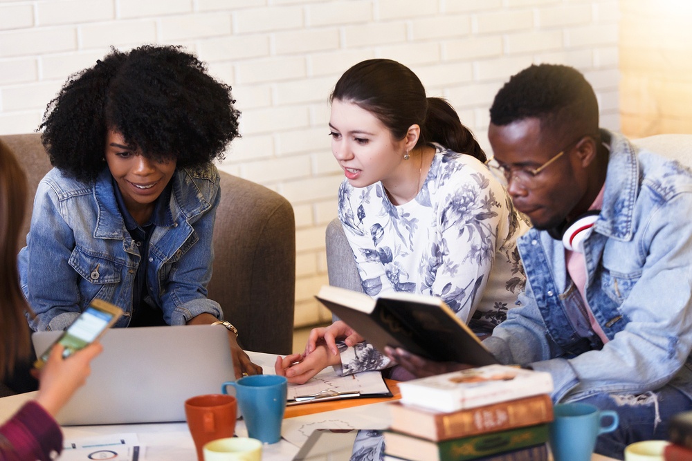 diverse group of college students discuss over books and computer